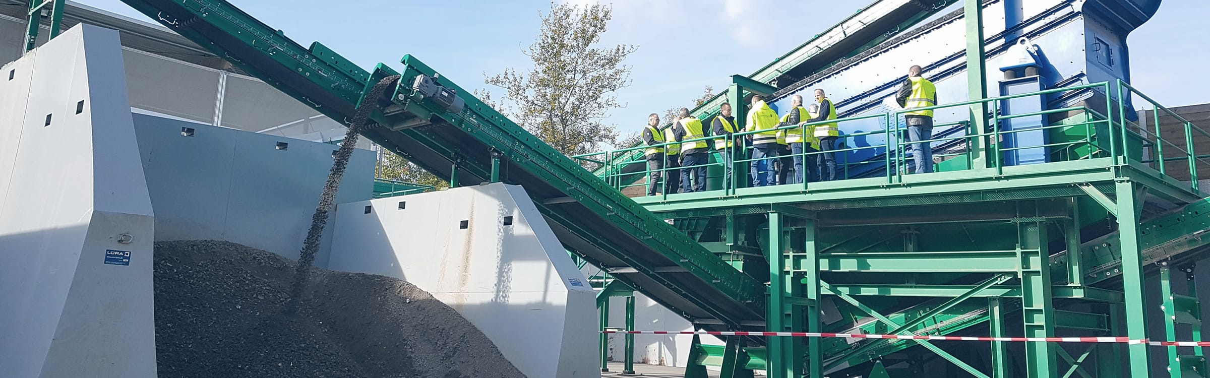 Anlage zur Bodenaufbereitung mit Transportband in Betrieb wird von Mitarbeitenden besichtigt | Nachhaltige Sandproduktion bei der GWM – Gesellschaft zur Weiterverwendung von Mineralstoffen – des Kreis Unna.